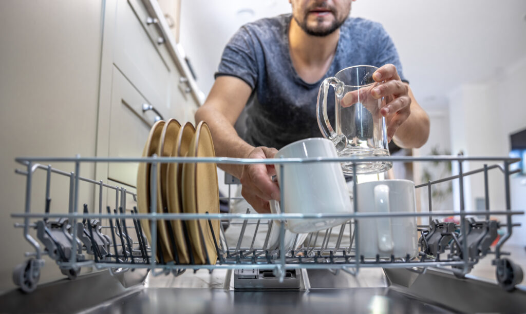 Uomo davanti alla lavastoviglie aperta mentre sistema le stoviglie nel cestello